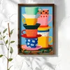 WallXpert uramljena MDF slika NAL012-46, naslagane šarene šolje i tanjirići na plavoj pozadini, 35,5 x 47 cm