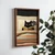 WallXpert uramljena MDF slika NAL111-70, crna mačka čita knjigu u krevetu pod prugastim ćebetom, 50 x 70 cm